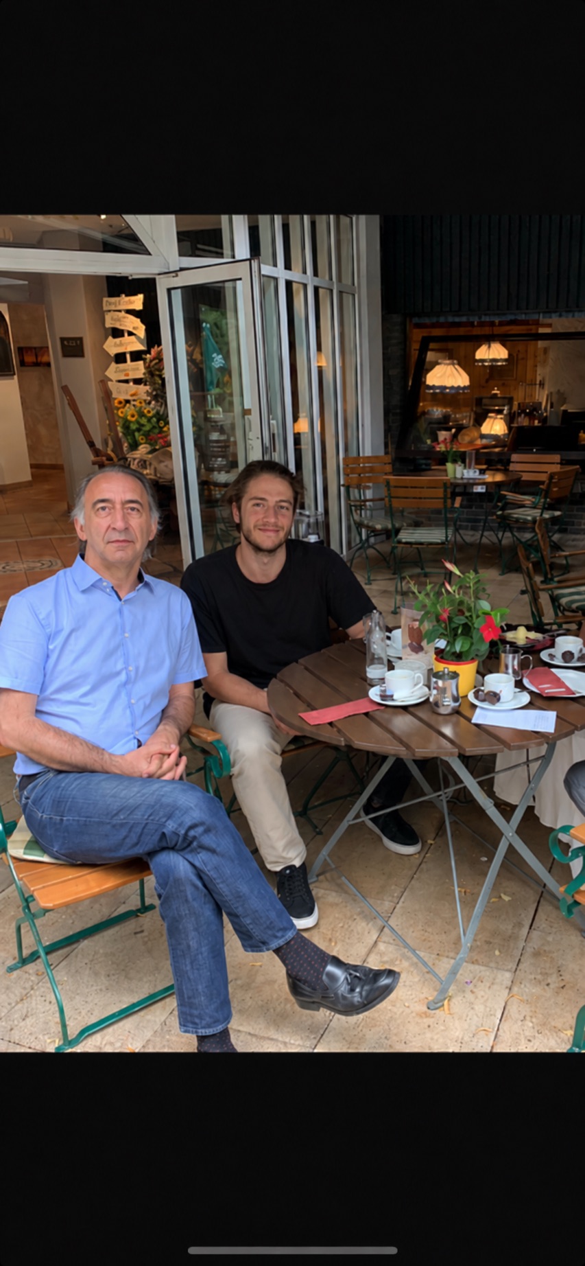 Kourosh Ghaffari sitting beside his dad at an outdoor café