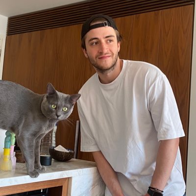 Kourosh Ghaffari, founder of Voicy, standing beside a grey cat